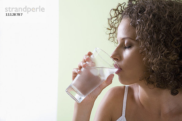 Gemischtrassige Frau trinkt ein Glas Wasser