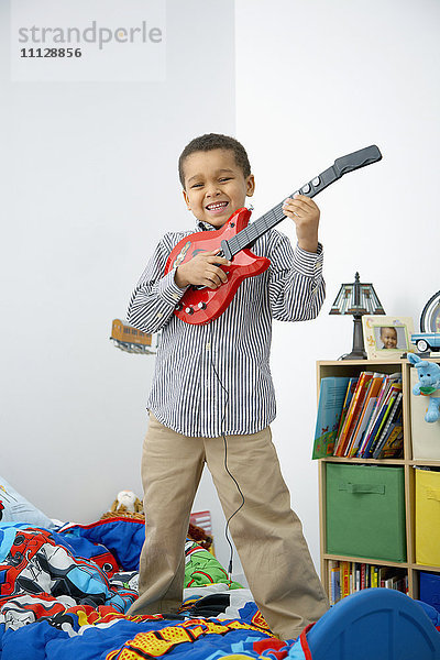 Gemischtrassiger Junge spielt Spielzeuggitarre