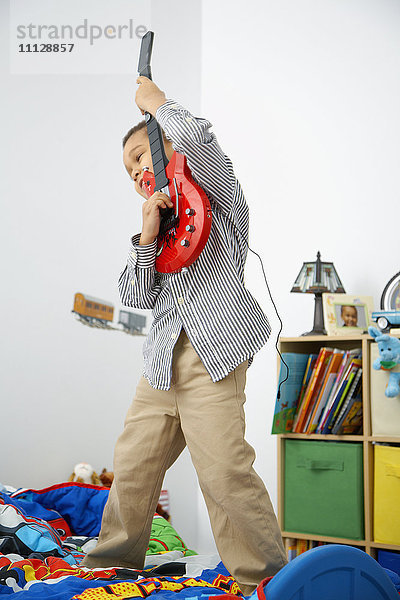 Gemischtrassiger Junge spielt Spielzeuggitarre