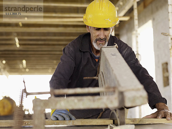 Spanischer Arbeiter mit Säge auf einer Baustelle