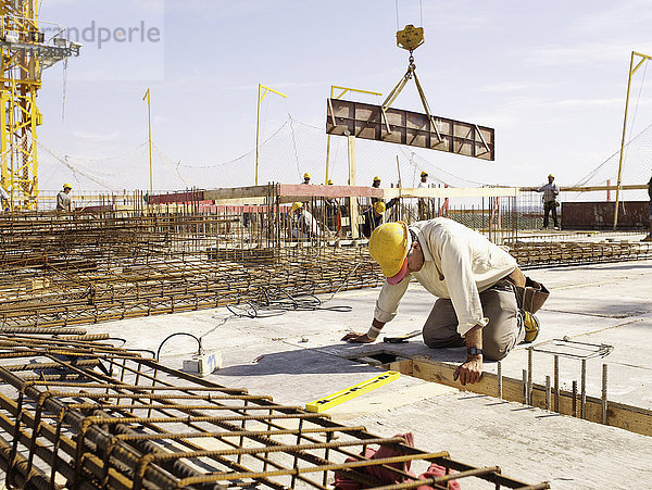 Hispanischer Arbeiter kniend auf der Baustelle