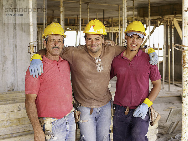 Hispanische Arbeiter umarmen sich auf der Baustelle