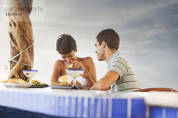 Hispanisches Paar beim Abendessen am Pool