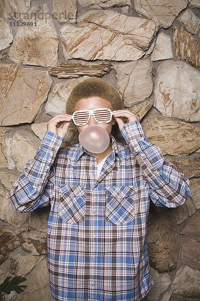 Gemischtrassiger Junge mit Sonnenbrille  der Kaugummi kaut