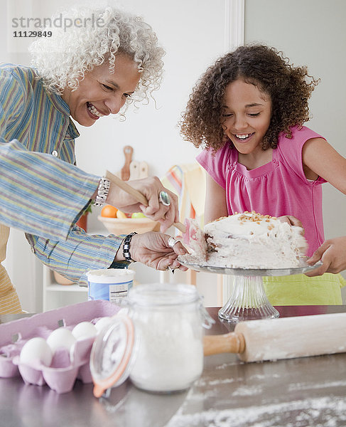 Großmutter und Enkelin glasieren Kuchen