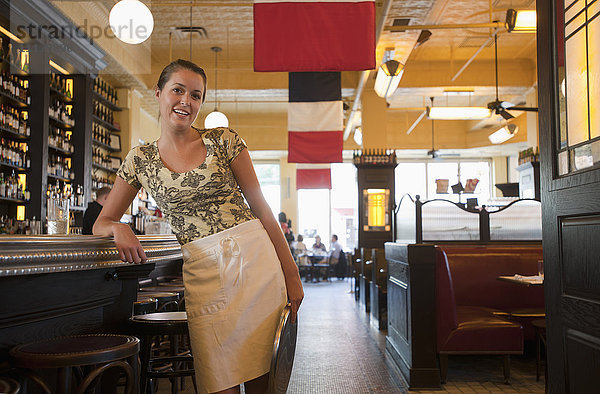 Kaukasische Kellnerin  die sich in einem Restaurant an die Bar lehnt