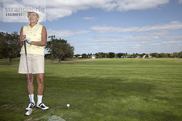 Ältere kaukasische Frau spielt Golf