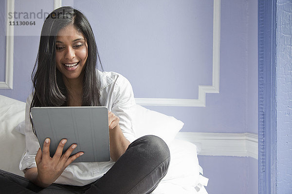 Sri Lankische Frau auf dem Bett mit digitalem Tablet