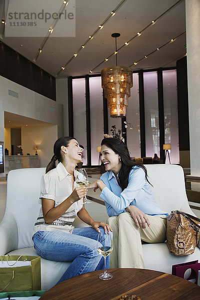 Hispanische Frauen trinken Weißwein in der Hotellobby