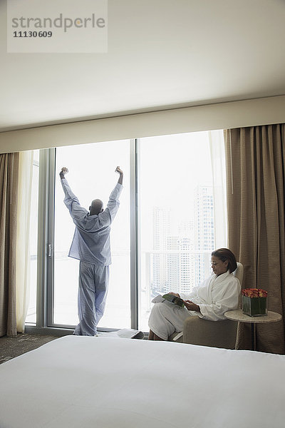 Paar in Pyjama und Bademantel am Fenster