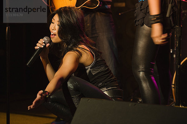 Asiatische Frau singt auf der Bühne