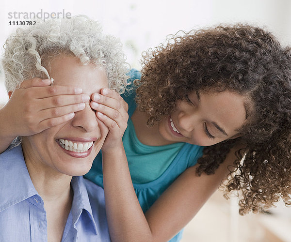 Enkelin bedeckt Großmutters Augen