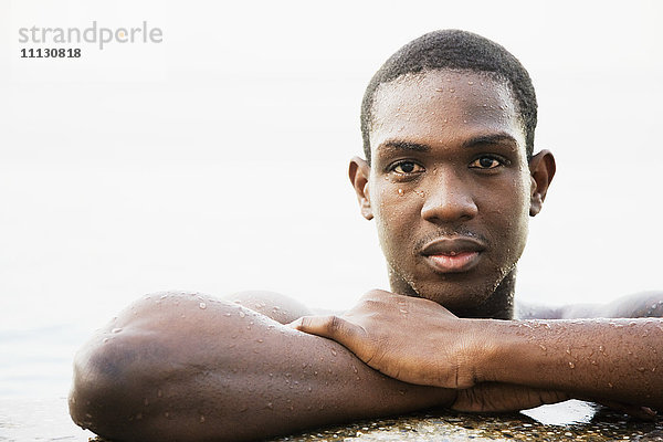 Afrikanischer Mann lehnt sich an den Rand eines Schwimmbeckens