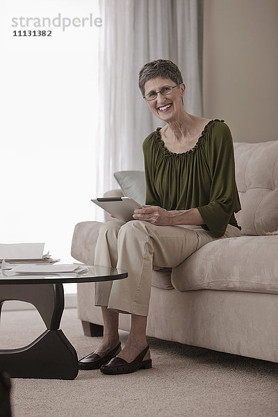 Kaukasische Frau mit digitalem Tablet auf dem Sofa