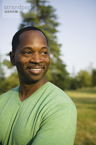 Lächelnder afroamerikanischer Mann im Park stehend