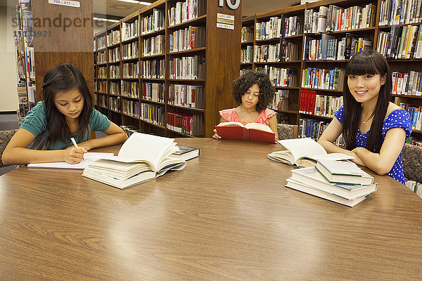 Mädchen machen Hausaufgaben in der Bibliothek