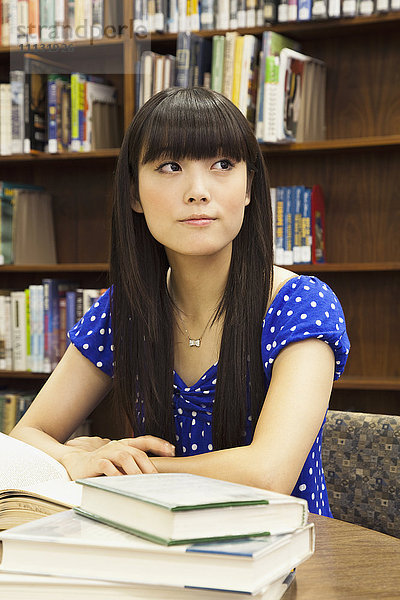 Asiatische Frau macht Hausaufgaben in der Bibliothek