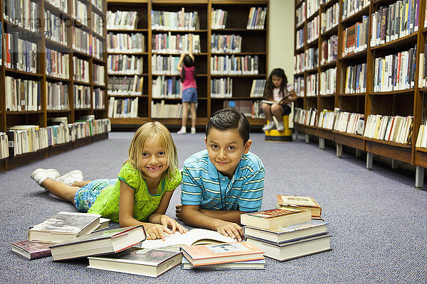 Kinder lesen Bücher auf dem Boden der Bibliothek