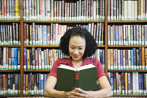 Afrikanische Frau liest ein Buch in der Bibliothek