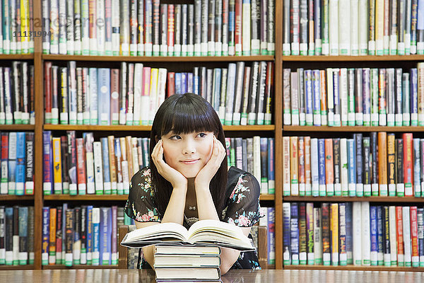 Asiatische Frau träumt in der Bibliothek