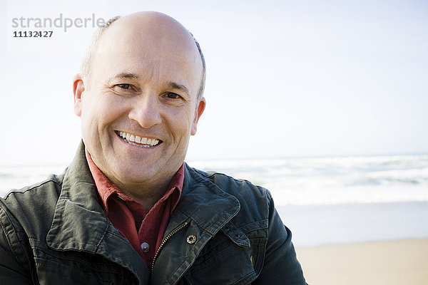 Lächelnder kaukasischer Mann am Strand stehend