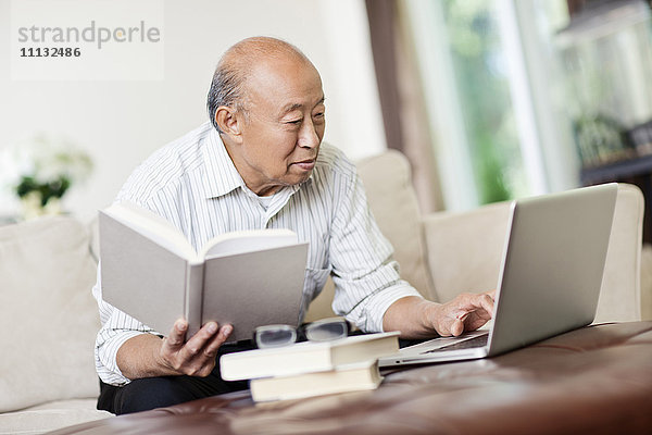 Chinesischer Mann mit Buch und Laptop