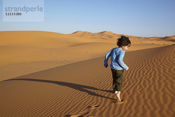 Gemischtrassiger Junge läuft in der Wüste