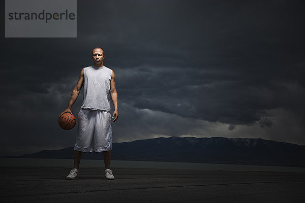 Gemischtrassiger Basketballspieler mit Gewitterwolken in der Ferne