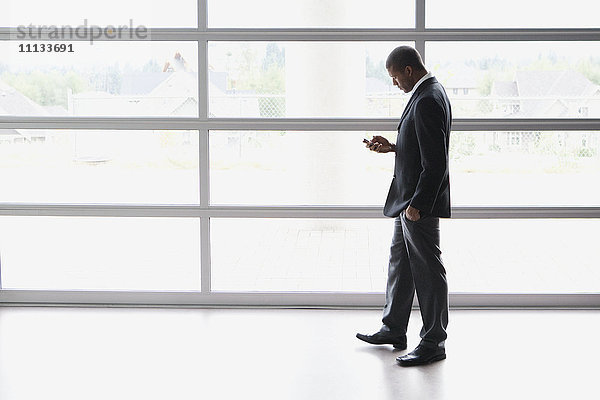 Afrikanischer Geschäftsmann mit Textnachrichten auf seinem Mobiltelefon
