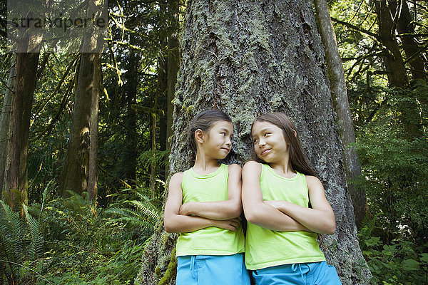 Gemischtrassige Mädchen lehnen sich an einen Baum