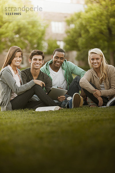 Zusammensitzende Studenten im Gras