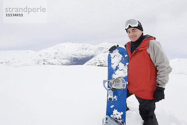 Älterer hispanischer Mann beim Snowboarden