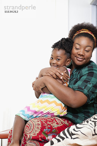Afroamerikanische Mutter hält Tochter auf dem Schoß
