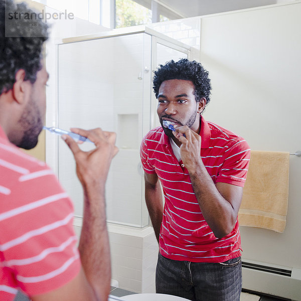Schwarzer Mann im Badezimmer beim Zähneputzen