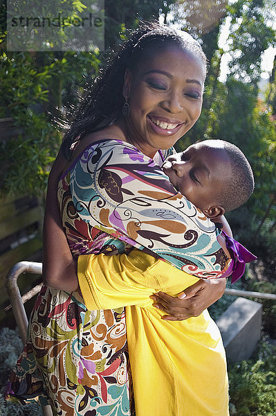 Schwarze Mutter  die ihren Sohn im Freien umarmt
