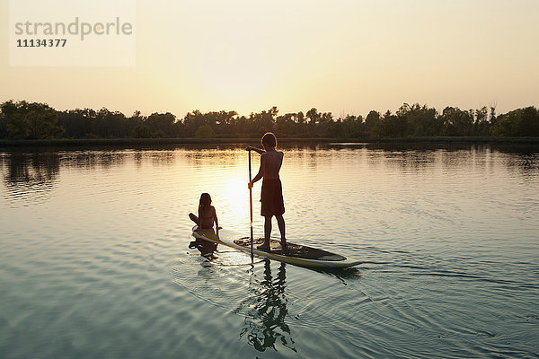 Kaukasischer Junge und Mädchen auf Paddleboard auf See