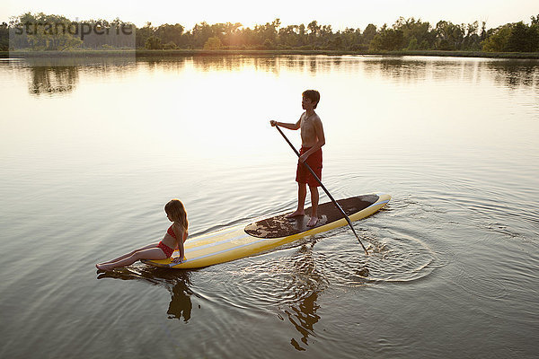 Kinder auf dem Paddelbrett auf dem See