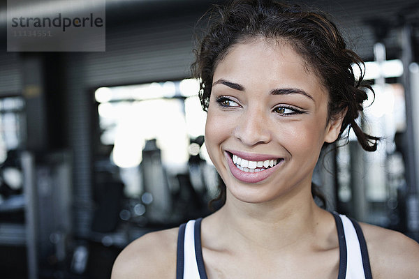 Lächelnde gemischtrassige Frau im Fitnessstudio