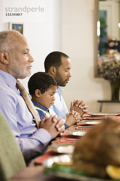 Afroamerikanische Familie spricht das Tischgebet beim Abendessen