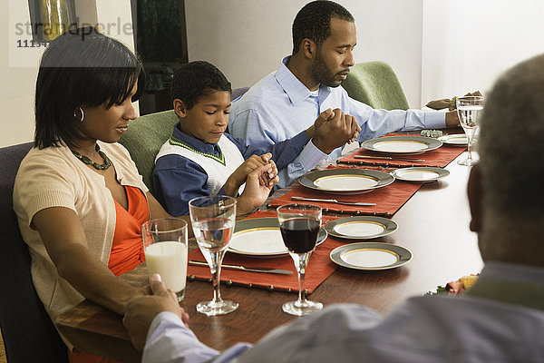 Afroamerikanische Familie spricht am Esstisch das Tischgebet