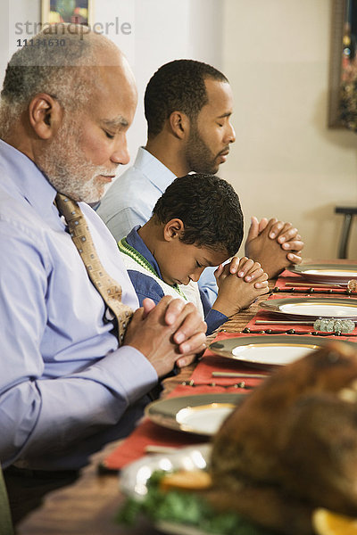 Afroamerikanische Familie spricht am Esstisch das Tischgebet