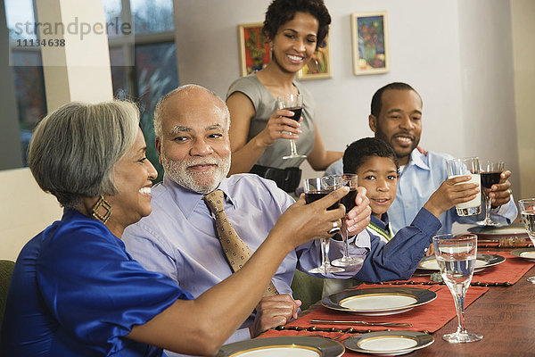 Afroamerikanische Familie stößt am Esstisch mit Wein an