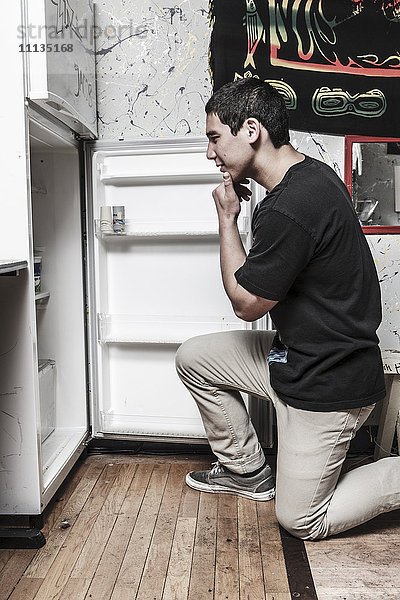 Gemischtrassiger Mann schaut in den Kühlschrank