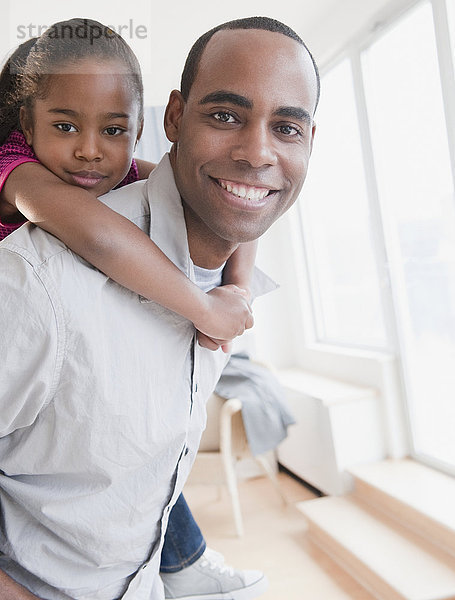 Afroamerikanischer Vater trägt Tochter auf dem Rücken