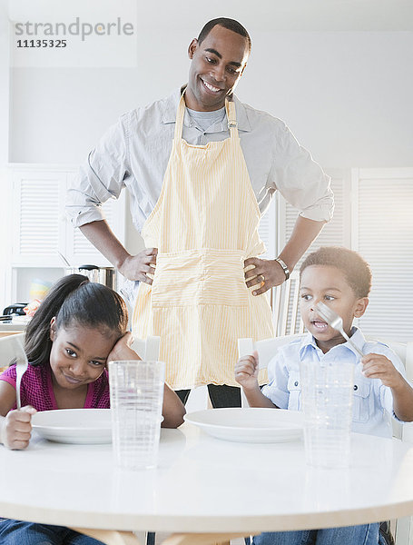 Afroamerikanischer Vater bereitet das Abendessen für seine Kinder vor