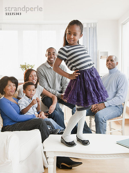Afroamerikanische Familie beobachtet die auf dem Tisch stehende Tochter