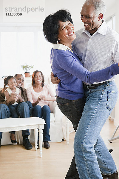 Afroamerikanischer Mann tanzt mit Frau im Wohnzimmer