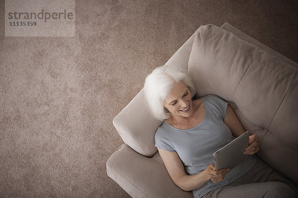 Kaukasische Frau mit digitalem Tablet auf dem Sofa