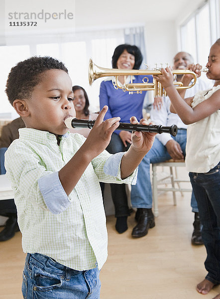 Afroamerikanische Familie beobachtet Kinder beim Spielen von Instrumenten
