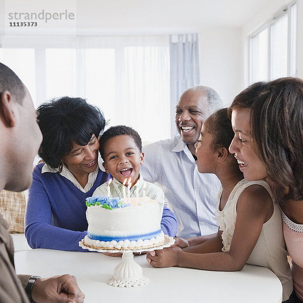 Afroamerikanische Familie beobachtet Enkel beim Ausblasen von Geburtstagskerzen